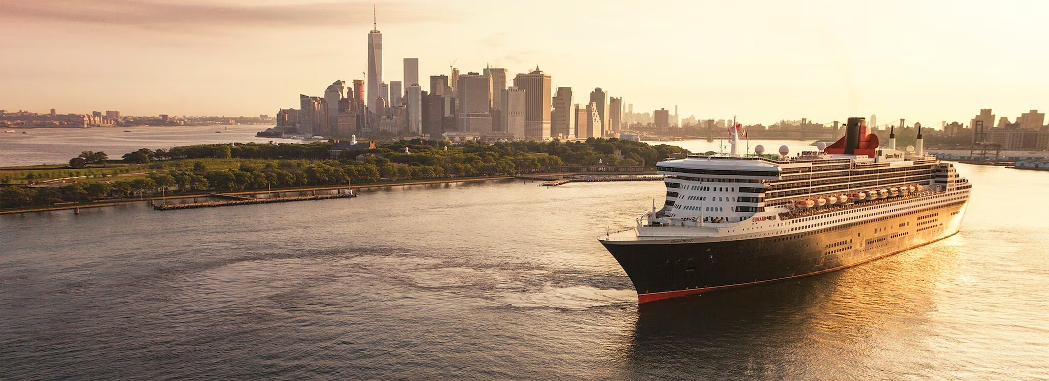 The Queen Mary 2 sailing past the Manhattan skyline at golden hour