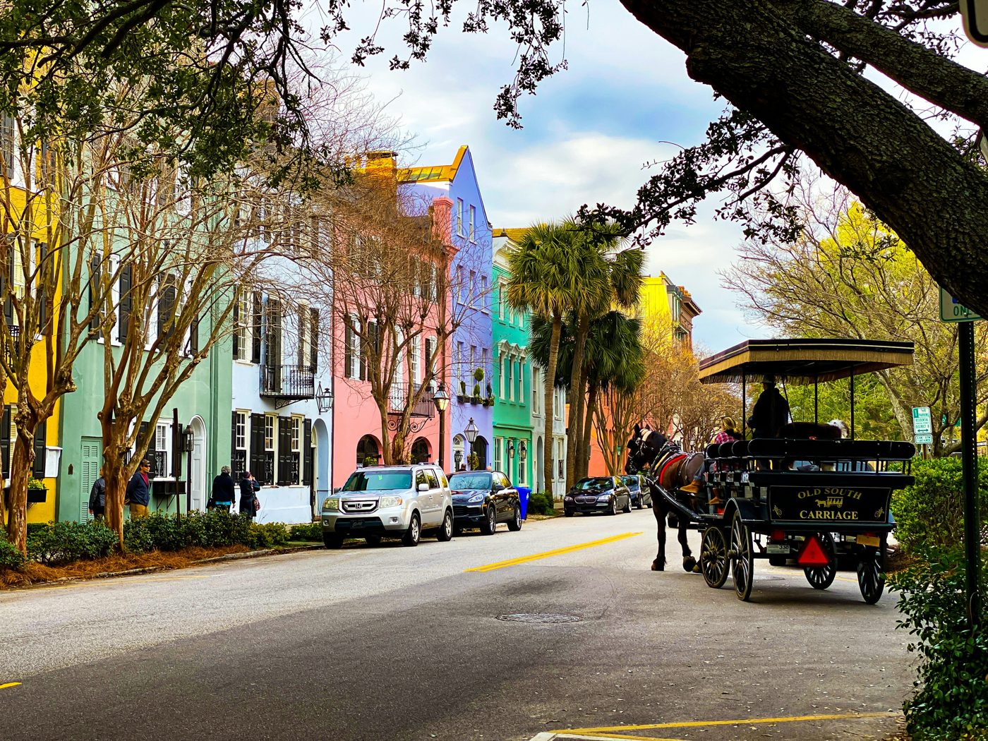 The pastel houses of Charleston's Rainbow Row with a horse-drawn carriage passing by