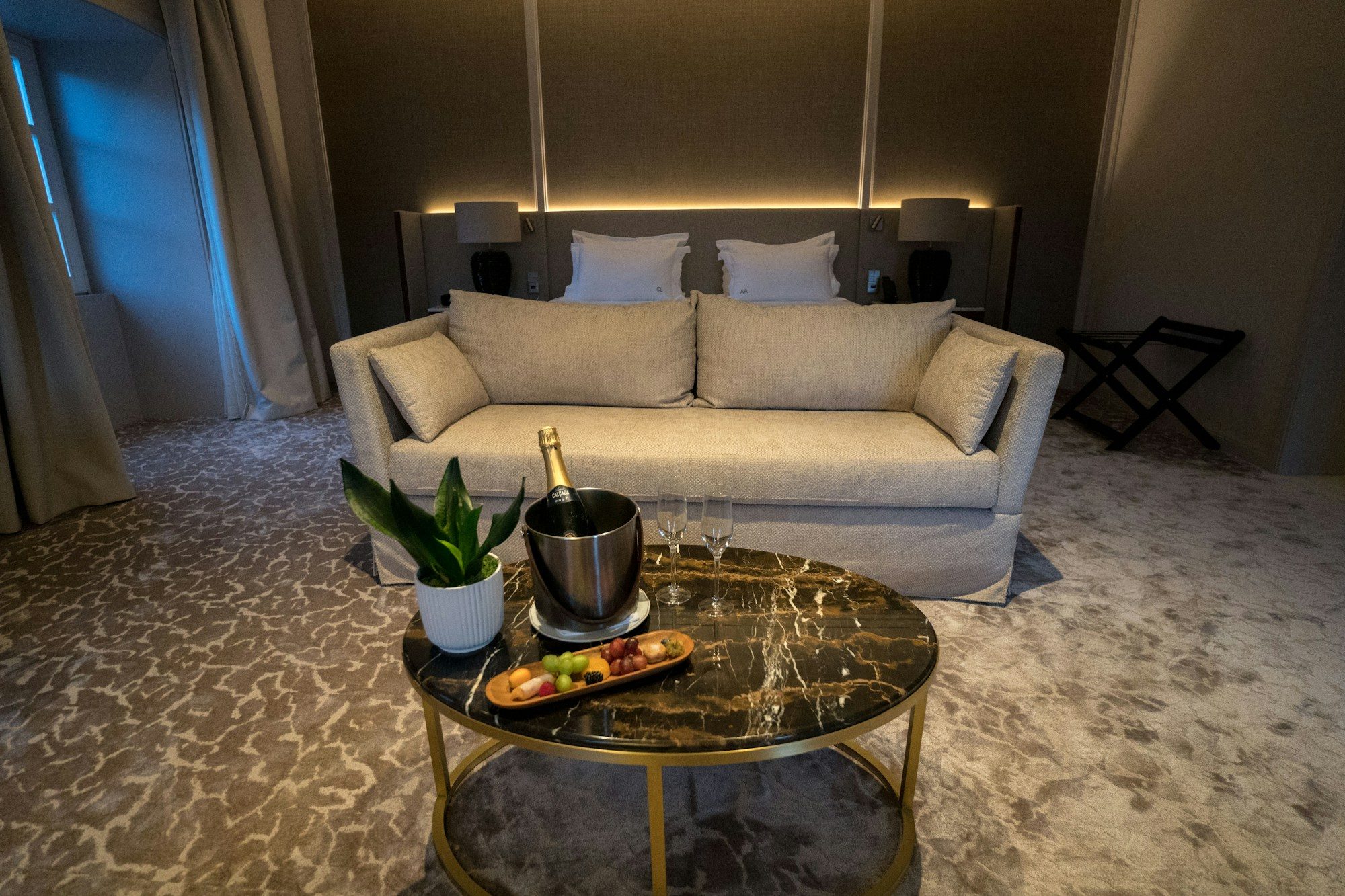 A luxurious hotel suite set with champagne in warm evening light.