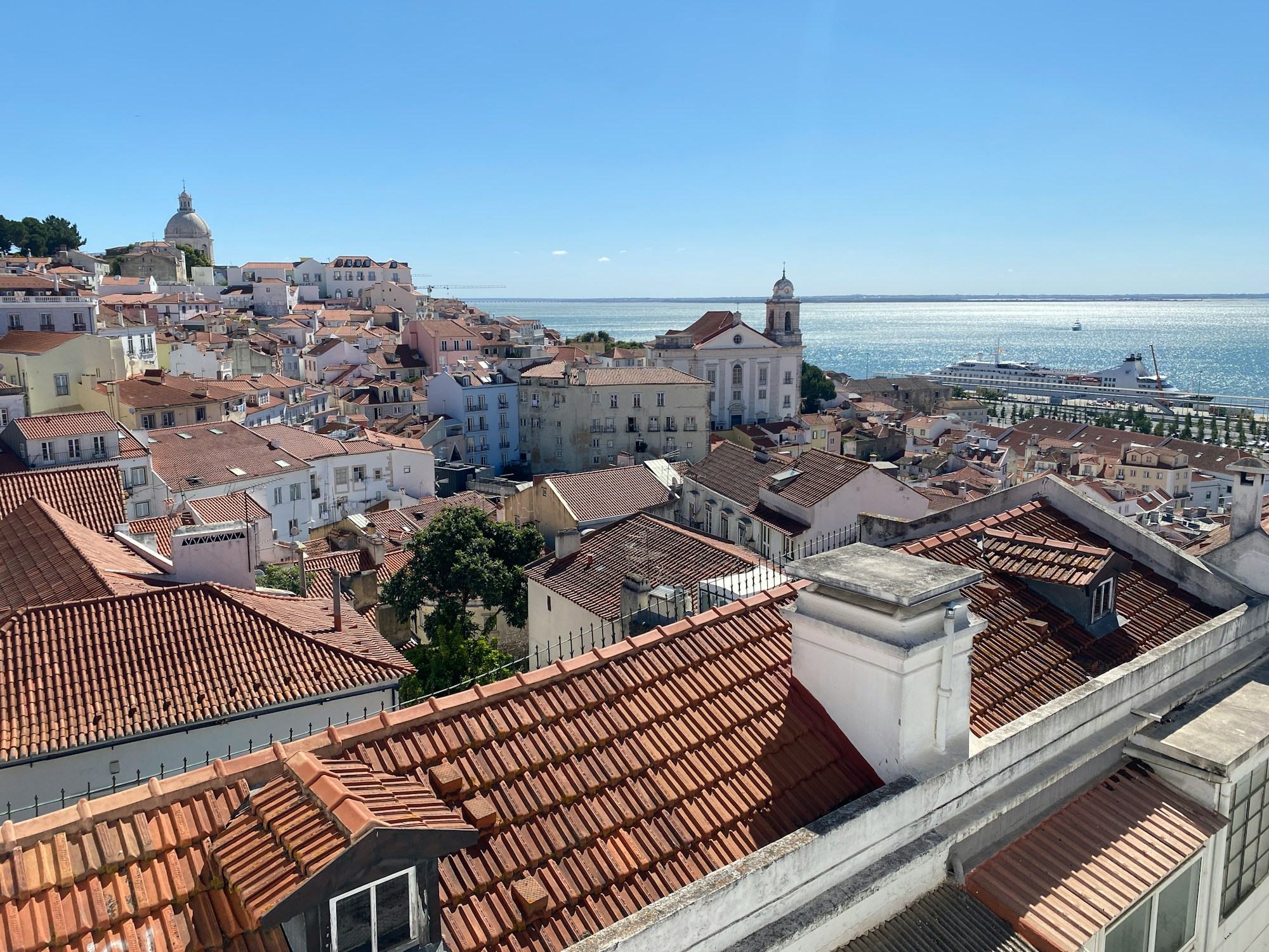 Lisbon's tiled rooftops tumbling down toward the Tagus.