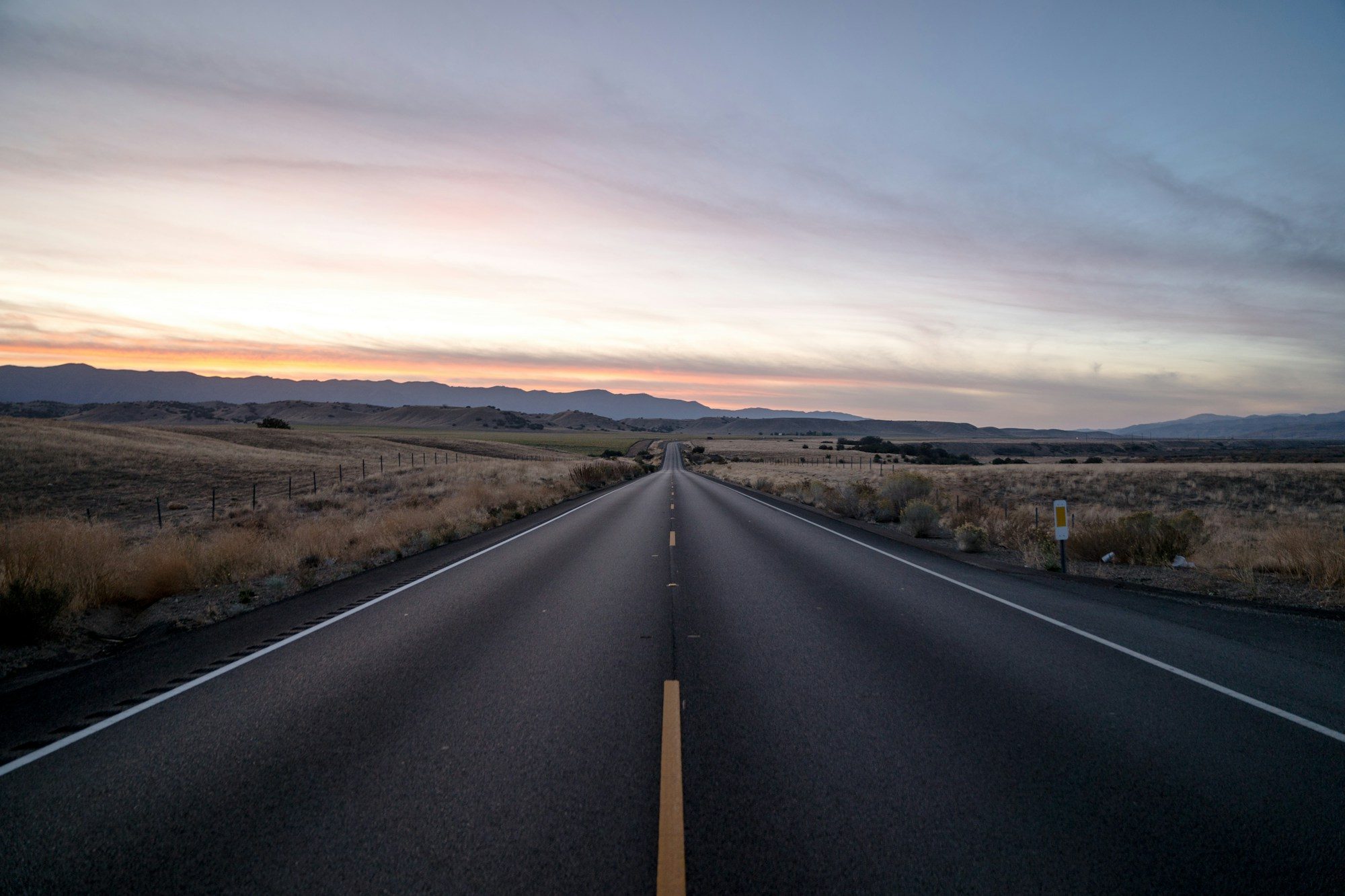 An open road running straight through wide, empty steppe.