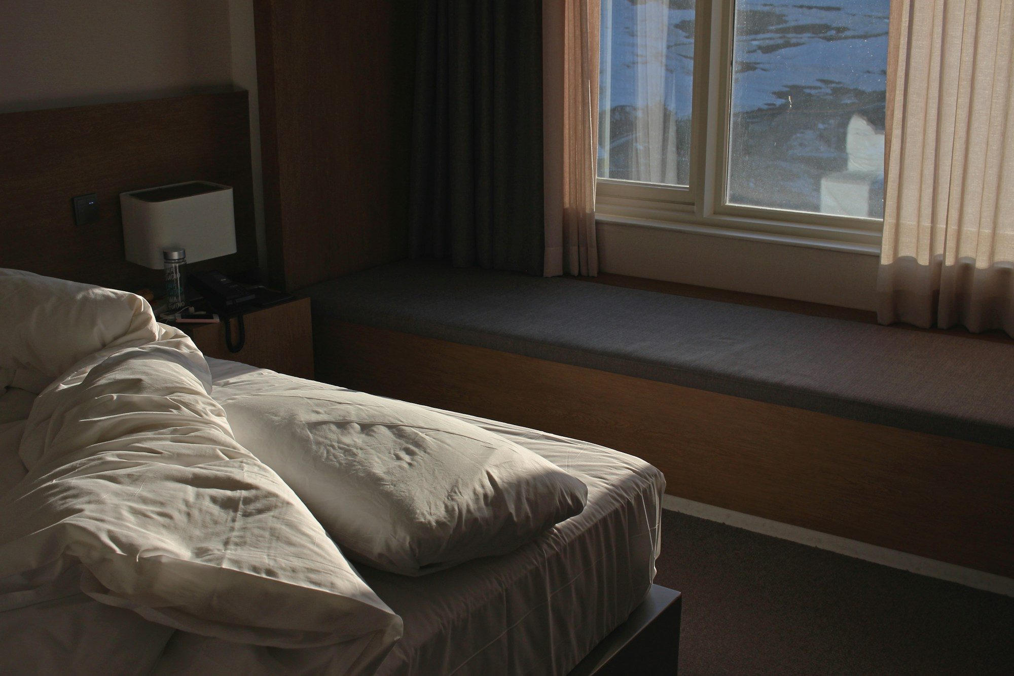 White linen and soft daylight by a curtained window.