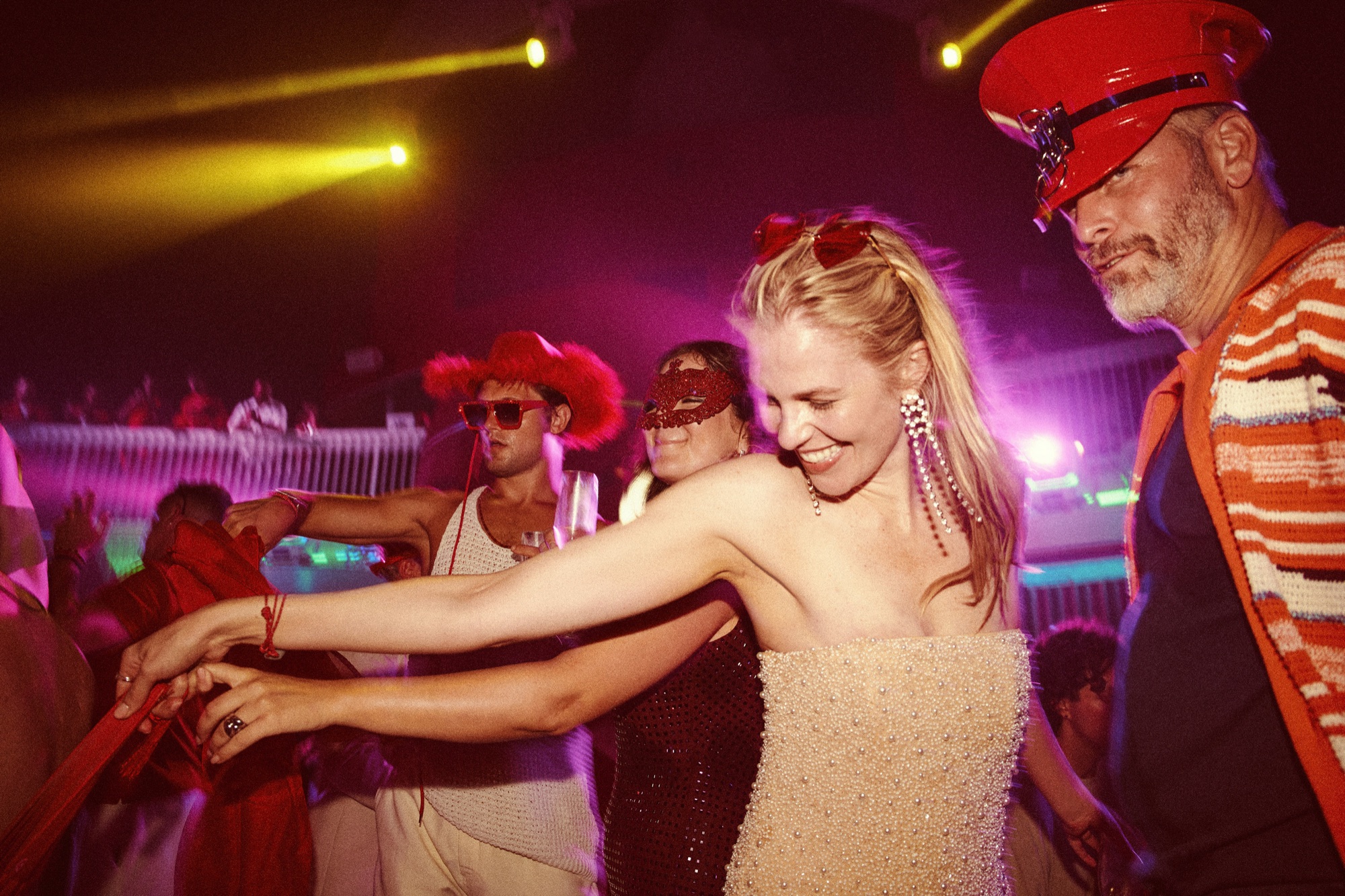 A jubilant crowd dancing together under coloured light